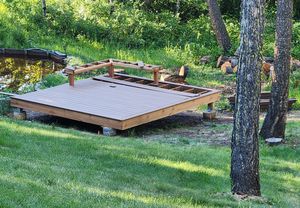 Freestanding deck built next to a pond with benches and composite decking.