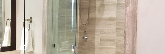 Custom glass shower with light wood-look tile walls and built-in bench installed in Bozeman bathroom remodel