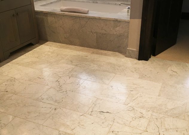 Polished marble floor tile installed in a Bozeman master bathroom with tub surround and custom stonework