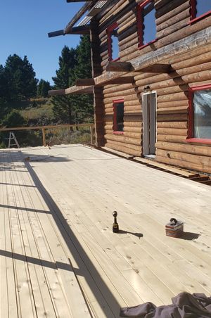 A deck being build and attached to a log cabin on top of a mountain. 