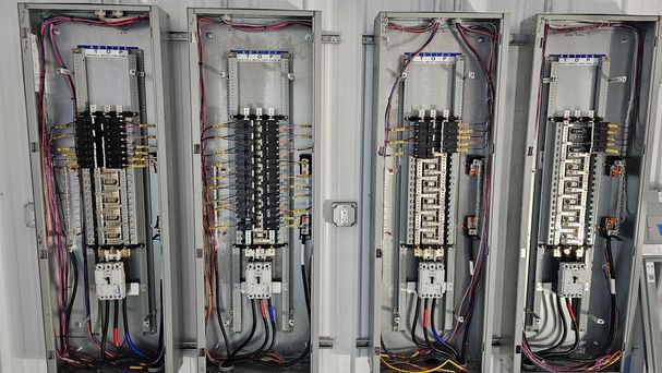 Four newly installed commercial electrical service panels with neatly organized wiring and breakers at a Bozeman job site