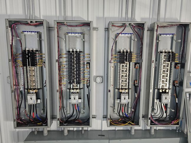 Four newly installed commercial electrical service panels with neatly organized wiring and breakers at a Bozeman job site